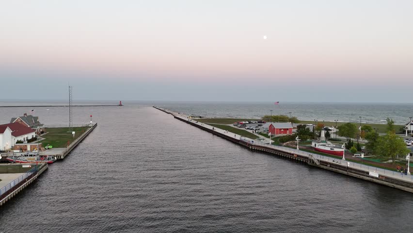 Aerial of Sheboygan Wisconsin USA at dusk on the shore of Lake Michigan.  Early Fall evening, slow approach shot of lighthouse under moonlight.