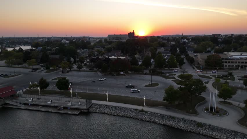 Aerial of Sheboygan Wisconsin USA at dusk on the shore of Lake Michigan.  Early Fall evening, slow approach shot of golden sun over downtown.