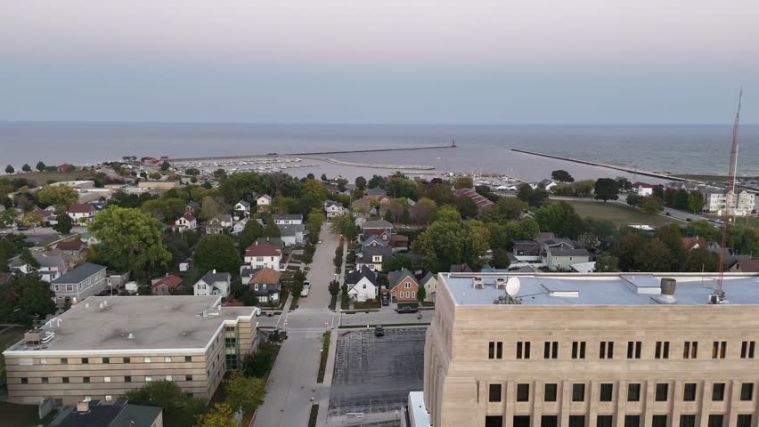 Aerial of Sheboygan Wisconsin USA at dusk on the shore of Lake Michigan.  Early Fall evening, left to right drone shot of harbor.