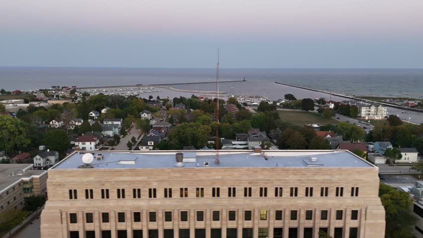 Aerial of Sheboygan Wisconsin USA at dusk on the shore of Lake Michigan.  Early Fall evening, right to left drone shot of harbor.