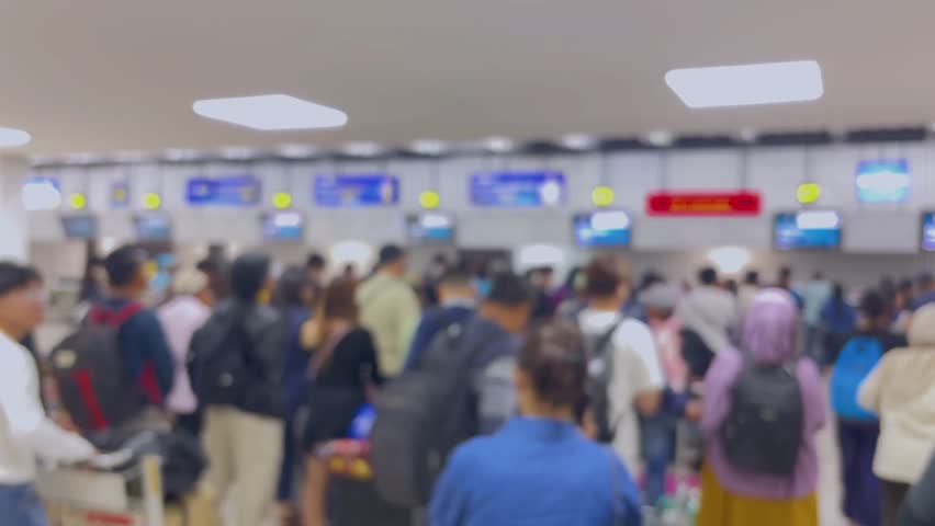 Passengers queue to board a plane at the airport terminal. Blur video.