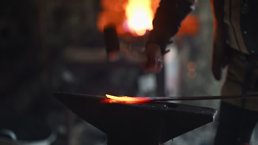 A Viking blacksmith with a white beard and braided hair works intently at a forge, hammering glowing metal on an anvil, with flames flickering in the background of a stone workshop cinematic slow