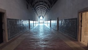 Convent of Christ in Tomar, Portugal, revealing a long cloister corridor with vaulted ceiling, tiled walls, and bright doorway light, handheld tilt upwards view - Powered by Shutterstock - Get 15% off with code: PIKWIZARD15