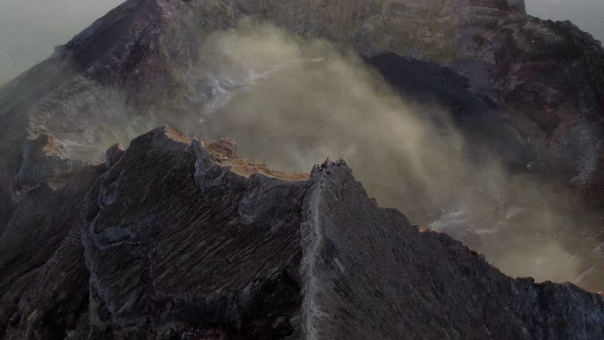Dense volcanic smoke drifting from Mount Agung crater under cloudy sky, Indonesia at sunrise