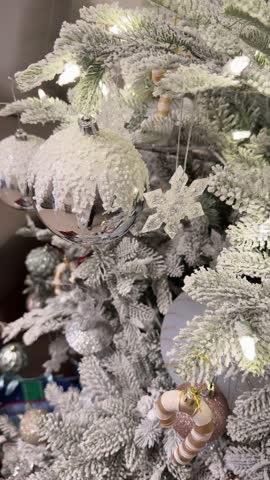 Snowy Christmas tree with white ornaments and festive decorations