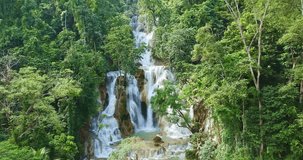 An aerial view of Tat Kuang Si Falls reveals its breathtaking multi-tiered cascades flowing into vivid turquoise pools, surrounded by dense tropical jungle in northern Laos. - Powered by Shutterstock - Get 15% off with code: PIKWIZARD15