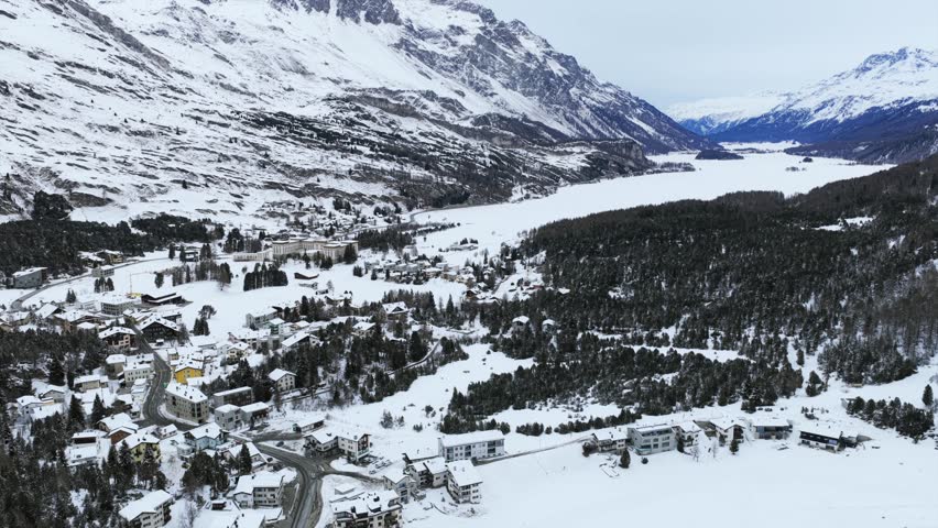 Maloja village and the frozen Lake Sils in the Engadin valley, Swiss Alps. Aerial drone panoramic view