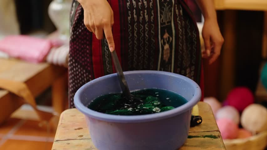 Artisan dips yarn into natural dye for handmade textile weaving