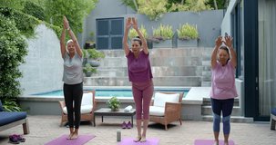 Senior mature women following center cue folding forward on patio mats to stretch rising to breathe. Outdoor, yoga, group, elder, standing, backyard, wellness - Powered by Shutterstock - Get 15% off with code: PIKWIZARD15