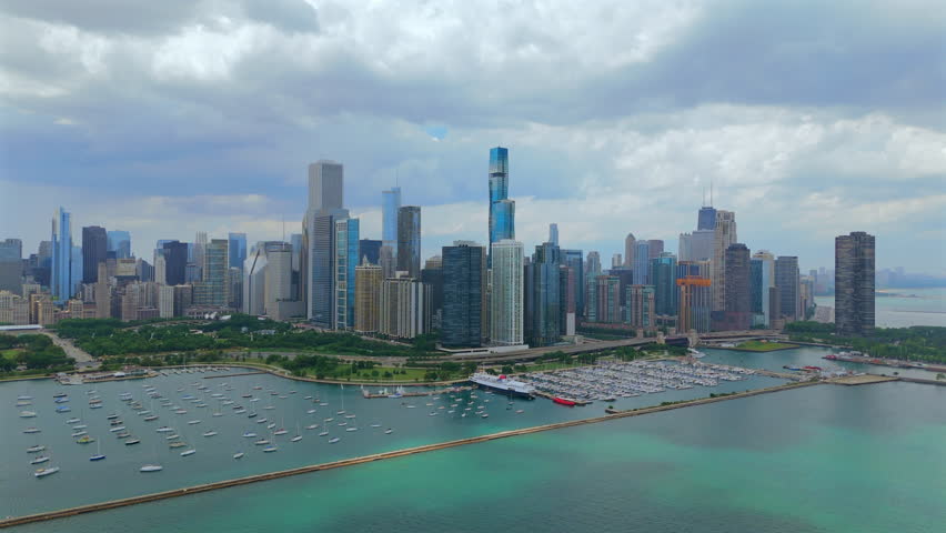 Wide aerial view of Chicago Illinois skyline with tall downtown towers, marina boats and turquoise Lake Michigan water, summer daylight, expansive cityscape and iconic urban waterfront.