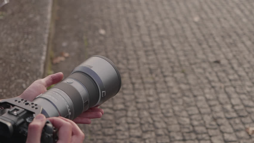 Close up of photographer hands holding camera with long lens outdoors