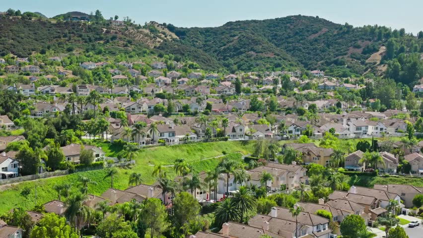 Aerial view of a suburban neighborhood nestled in the rolling hills of California, showcasing homes and scenic landscapes