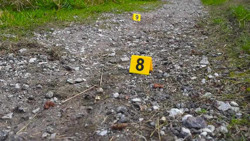 Upward camera move reveals numbered markers beside drag marks on countryside track under overcast sky.