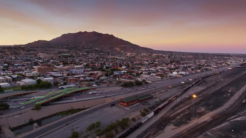 Scenic aerial sunset view of El Paso, Texas, with city lights glowing beneath the Franklin Mountains and a colorful desert sky on the horizon.