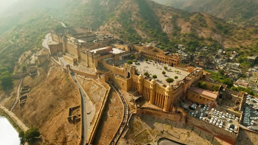 Aerial view of Amber Fort in Jaipur, Rajasthan, India, with mountains in the background, showcasing historic architecture and cultural heritage.
