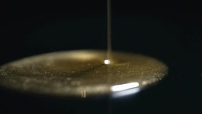 A thin stream of viscous golden liquid cascades onto a dark, reflective surface, creating ripples and shimmering highlights - Powered by Shutterstock - Get 15% off with code: PIKWIZARD15