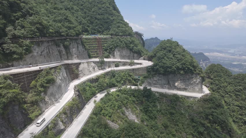 Stunning aerial perspective of the famous hairpin curves on the 99 Bends road at Tianmen Mountain. Ideal for travel documentaries and adventure tourism content.