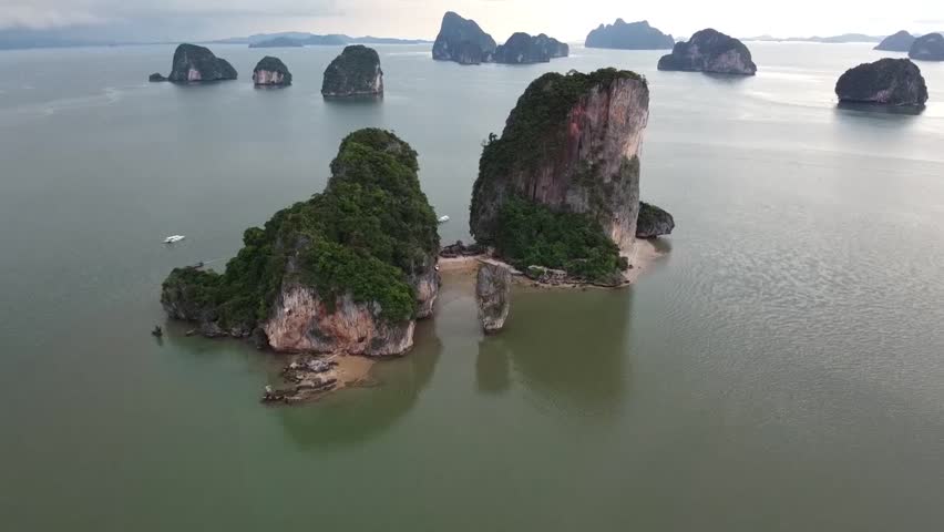 Aerial view of limestone islands rising from turquoise sea water in a tropical location.
