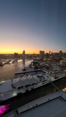 Panoramic view of the Baltimore city skyline and Inner Harbor at sunset with urban architecture and waterfront reflections. Vertical video. Timelapse.
