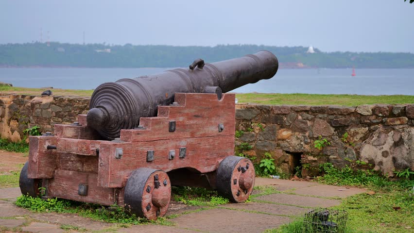 Historic Cannon on Wooden Carriage at Coastal Fort Overlooking Sea Landscape with Stone Wall and Green Grass under Daylight Sky