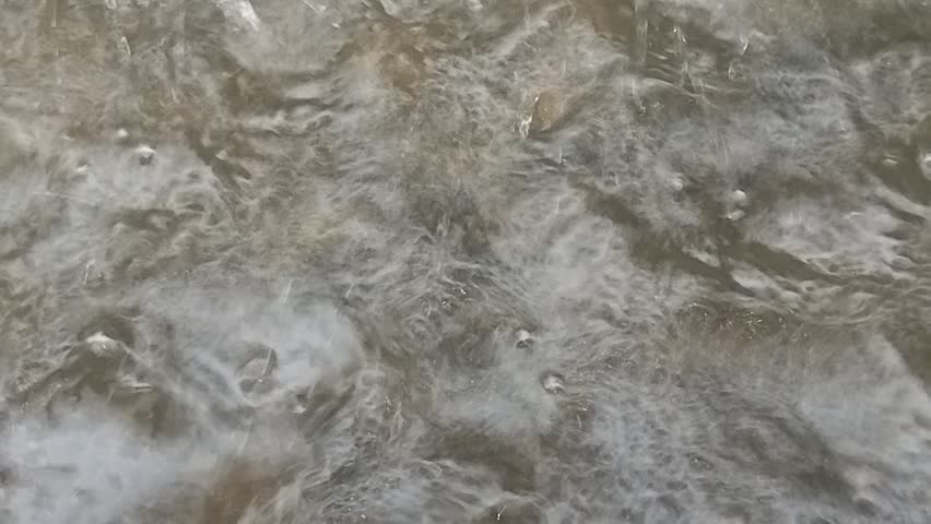 Heavy Raindrops Falling into Muddy Water Surface Close Up