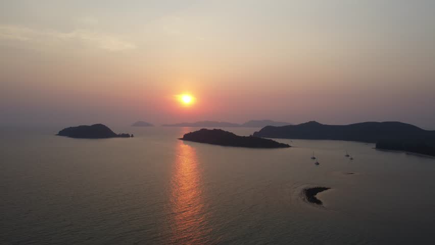 Peaceful sunset drone footage over tropical waters and small islands surrounding Koh Mak in Thailand, Southeast Asia.