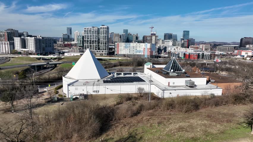 Aerial view of Nashville, Tennessee, with modern architecture Adventure Science Center near Fort Negley area with city skyline in background under clear blue sky on sunny day. Wide shot. Flyover.