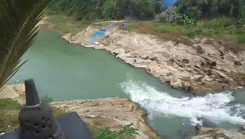 Scenic wide view of a turquoise river with white water rapids and rocky banks.