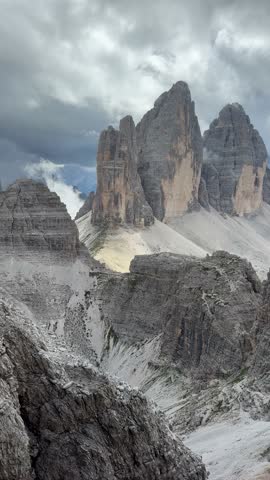Iconic rock towers Cima Grande, Cima Ovest and Cima Piccola forming the famous Tre Cime di Lavaredo massif in the Dolomites, Italian Alps. Majestic limestone peaks rising above alpine landscape under dramatic sky.