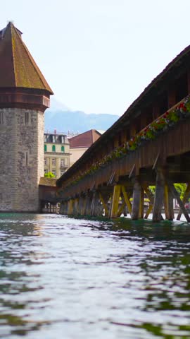 Historic wooden bridge in Lucerne with tower by the lake in Switzerland on a sunny day