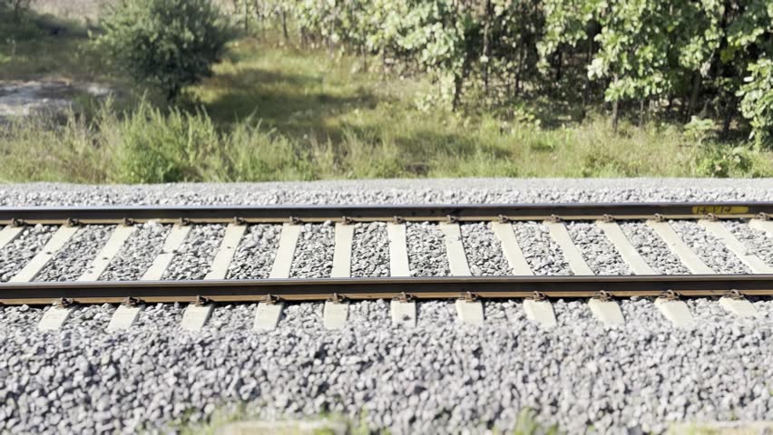 Railway tracks at sunset Steel rails and wooden sleepers on gravel ballast. Perspective lines leading forward. Transportation infrastructure detail. Travel and journey concept 