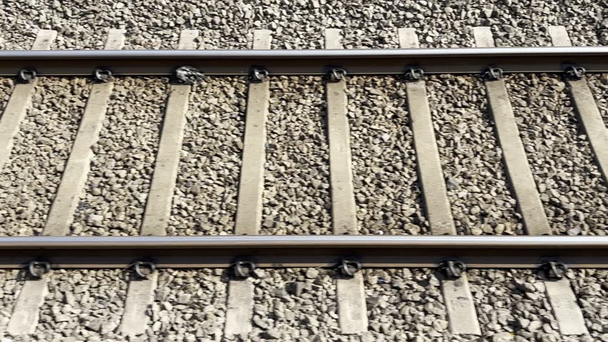Railway tracks at sunset Steel rails and wooden sleepers on gravel ballast. Perspective lines leading forward. Transportation infrastructure detail. Travel and journey concept 