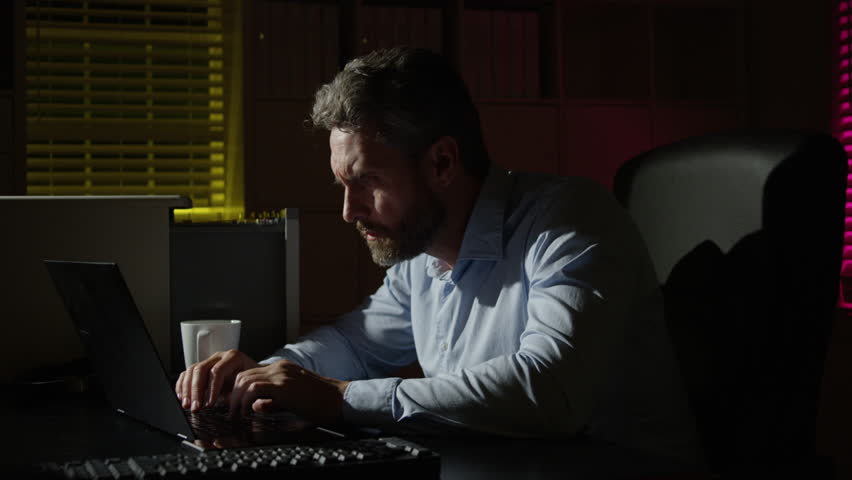 Night office scene with man working late. Business man suffering from insomnia and stress. Tired male office worker working late at night. Overtime work. Stressed business man working late.