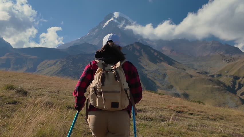 Hiker walking to Mount Kazbek with icy peak.