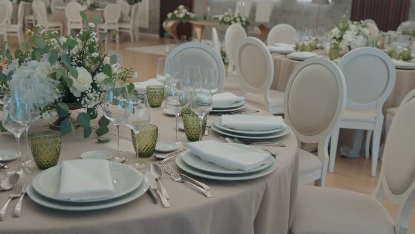 Round banquet table prepared with layered plates folded napkins glassware and soft white floral centerpiece