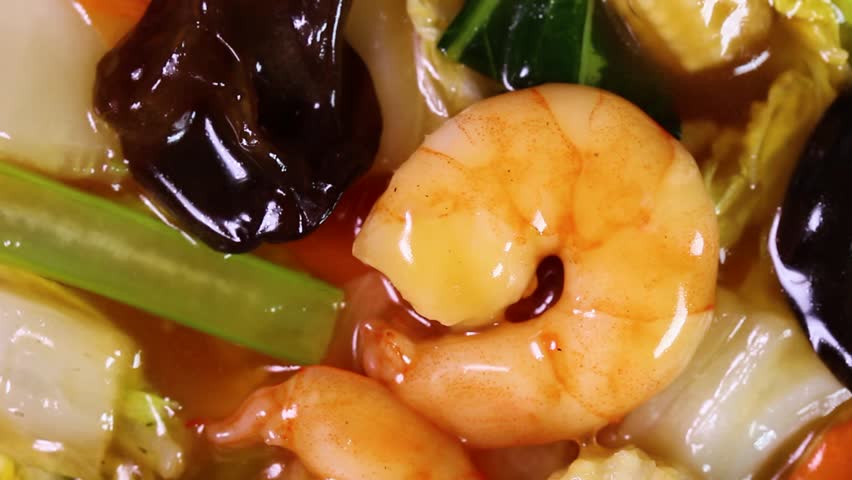 Rotating close-up of seafood gomoku ankake don, japanese rice bowl topped with seafood and vegetables in a thick savory glaze