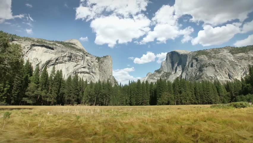 Scenic view of Yosemite Valley National Park with towering mountains, lush trees, and a clear blue sky, highlighting its iconic natural beauty.