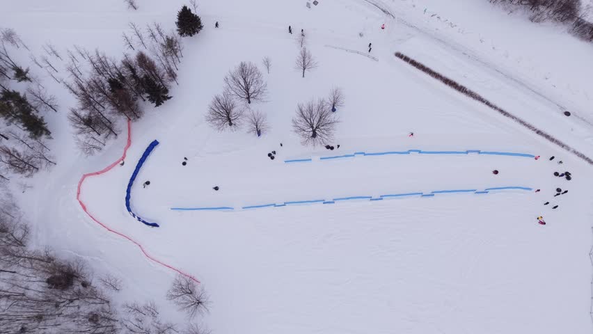 Aerial top down view of winter snow tubing track with people enjoying outdoor recreation.