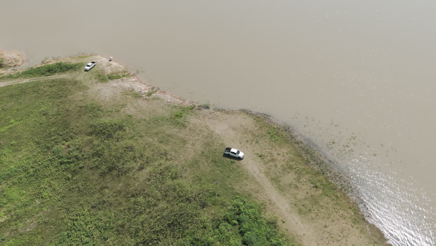 Aerial drone footage of a pickup truck driving on a rural road through countryside landscape. Scenic view of travel, transportation, and freedom in nature