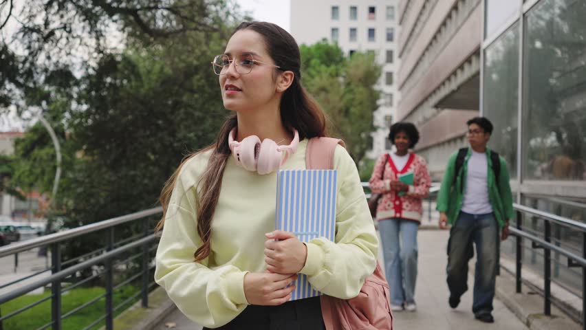 Hispanic student woman going to classes with group of college friends walking towards University building