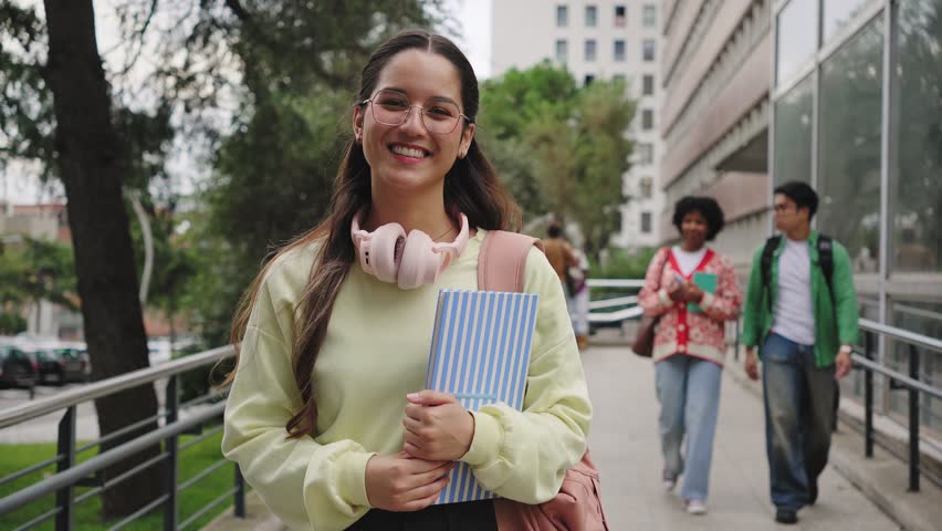 Hispanic student woman going to classes with group of college friends walking towards University building