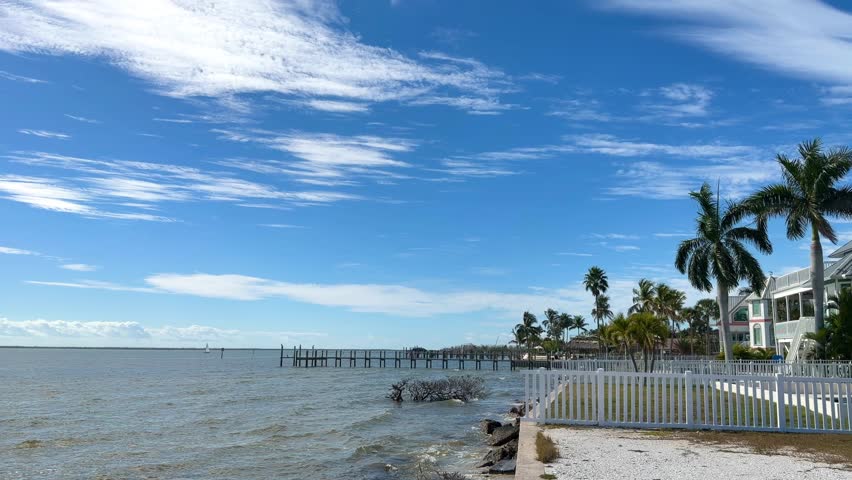 Waterfront properties and palm trees line the coast along 1st Avenue in St James City, Florida, under a bright blue sky, offering a warm destination for Christmas and holidays