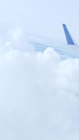 view from an airplane window showing the aircraft wing flying through thick white clouds in the sky.Soft natural light and dreamy atmosphere create a peaceful travel and aviation concept.                                          