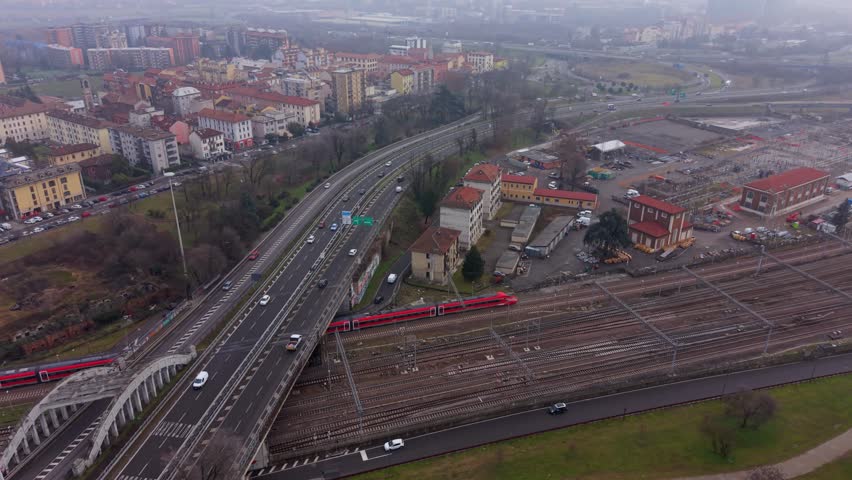 Passenger Train Running Parallel to Highway Near Milan Aerial