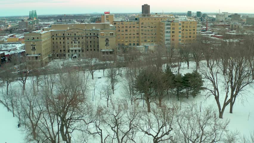 drone flying over lake in park lafointaine montreal winter fron notre dame hospital to main building in the middle of parc