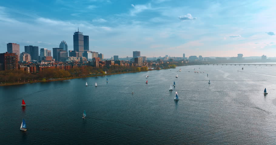 Multiple sailboats on the waterscape of the Charles River in Boston, Massachusetts, USA. Drone footage over the river revealing view on the skyline of the city.