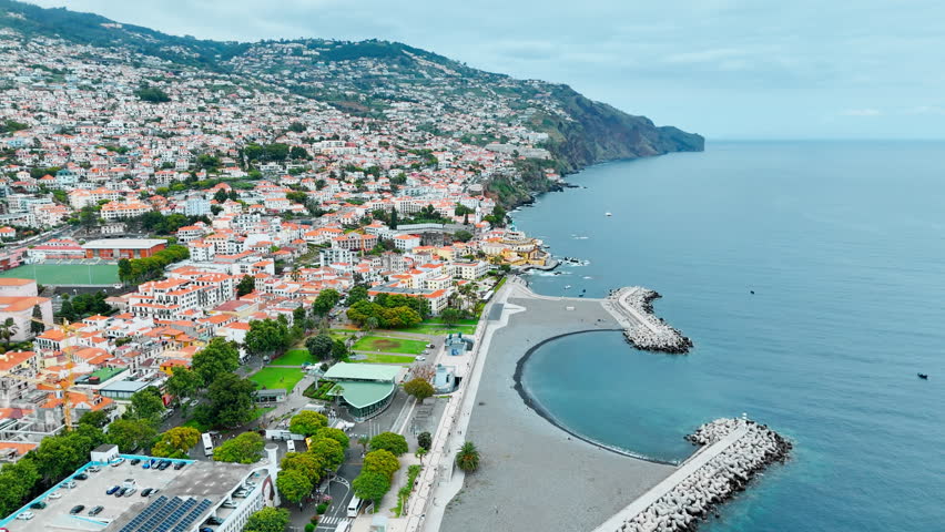 Aerial view of dense urban coastline with waterfront roads and breakwaters in Funchal, Madeira