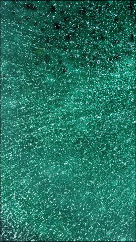 Close-up of mesmerizing liquids mixing with sparkles, vertical view