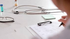 A concentrated female doctor filling out medical report at clipboard with stethoscope lab coat, drug medicine bottle, illustrating healthcare diagnosis and patient record review in hospital or clinic - Powered by Shutterstock - Get 15% off with code: PIKWIZARD15