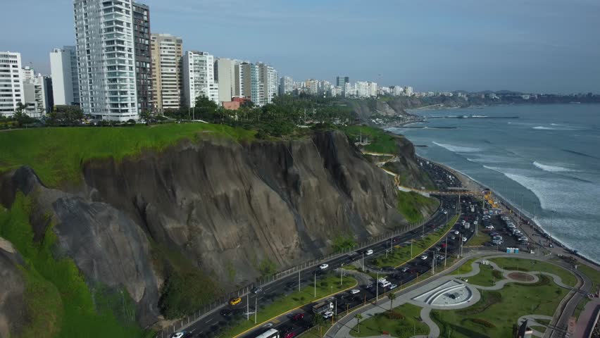 Aerial shot of coastal highway called "Costa Verde". On the left are hills with apartment buildings on top and to the right is the pacific ocean. Located in Miraflores district of Lima, Peru.